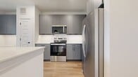 This 610 sq ft, one-bedroom, one-bathroom apartment in Argyle, TX features a bright, open-concept kitchen and living area with light hardwood flooring, recessed lighting, and a ceiling fan. The kitchen boasts gray shaker cabinets, stainless steel appliances, white quartz countertops, a center island with pendant lighting, and a built-in desk nook. The 130 sq ft bedroom offers plush carpet, a large window with natural light, and a walk-in closet with built-in shelving and dual hanging rods. The bathroom includes a blue-gray vanity, glass-enclosed shower, and hardwood-style flooring. A private door leads to an outdoor view.
