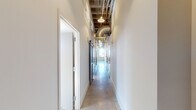 Located at 1909 First Ave N in Birmingham, Alabama, this single-floor space masterfully combines historic industrial character with contemporary design. The layout, as revealed in the floor plan, extends as a long, thoughtfully organized structure with distinct functional zones connected by a sleek corridor.

The hallways feature polished concrete floors, exposed ductwork, and an open ceiling with visible structural elements, establishing an industrial aesthetic throughout. Frosted glass doors and barn-style sliding doors add modern architectural detail while maintaining an open, airy feel.

The kitchen is a standout feature, equipped with stainless steel appliances, dark cabinetry with granite countertops, a subway tile backsplash, and a central island — all set against the backdrop of an exposed brick wall that reinforces the building's historic character.

Several open rooms showcase soaring ceilings with exposed wooden beams and ductwork, polished concrete floors, and arched windows that flood the space with natural light and offer views of the surrounding Birmingham cityscape. Raw brick walls with remnants of original plaster further highlight the building's heritage.

The bathroom features large-format tile walls, a spacious walk-in shower with a mosaic tile floor, and refined chrome fixtures, providing a refined contrast to the raw industrial elements found throughout the space.