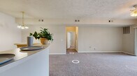 Located at Walden Creek Trace in Spring Hill, Tennessee, this one-bedroom, one-bathroom residence offers a thoughtfully arranged single-floor layout designed for comfortable everyday living. The open-concept living room is carpeted and filled with natural light through large sliding glass doors dressed with vertical blinds, complemented by a ceiling light fixture that adds warmth to the space. A peninsula counter transitions seamlessly into the kitchen, which features warm wood-toned cabinetry, white appliances including a refrigerator, range, microwave, and dishwasher, and easy-care wood-look flooring. The generously sized bedroom is carpeted and includes a ceiling fan, ample wall space, and a window with blinds that allows in natural light. It provides direct access to a spacious walk-in closet outfitted with multiple wire shelving tiers, maximizing storage capacity. The bathroom features wood-toned cabinetry with a white countertop vanity and wood-look tile flooring, connecting to a hallway with additional closet access. Neutral tones and textured ceilings are carried throughout, creating a cohesive and understated aesthetic well-suited to a variety of personal styles.