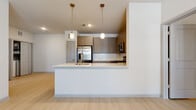This well-designed single-floor residence offers a clean, modern aesthetic throughout, with light wood-look flooring connecting each area of the home seamlessly. The open-concept kitchen serves as a central highlight, featuring warm taupe shaker-style cabinetry, a white subway tile backsplash, stainless steel appliances including a refrigerator, range, and microwave, and a peninsula with a white countertop and an undermount sink. Stylish pendant lighting hangs above the peninsula, adding an elegant touch to the space. The kitchen flows naturally into the open living area, creating an inviting, functional layout. Multiple bedrooms offer bright, airy environments, each equipped with ceiling fans and windows that invite natural light. One bedroom includes access to a generously sized walk-in closet outfitted with wire shelving on multiple walls, providing ample storage. The primary bathroom features a glass-enclosed walk-in shower with tile surround, taupe cabinetry with overhead storage, a white vanity countertop, and a framed mirror. A second full bathroom offers a soaking tub with a tiled surround and a matching vanity, maintaining the same cohesive, contemporary style found throughout the residence.