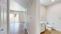 Located at 1456 E Pecos Rd in Gilbert, AZ, this single-floor unit offers a well-organized layout comprising a living room, kitchen, bathroom, and hallway. Light-toned wood-look flooring runs consistently throughout the space, creating a cohesive and clean aesthetic.

The living room is bright and open, benefiting from a sliding glass door that leads to a private balcony, allowing natural light to fill the area. A ceiling fan adds comfort, and neutral walls provide a versatile backdrop. A mirrored closet along one wall maximizes the sense of space.

The kitchen is efficiently designed in a galley-style configuration, featuring white shaker cabinetry, light countertops, and a full suite of stainless steel appliances including a refrigerator, electric range, and over-the-range microwave. The layout makes practical use of the available space while maintaining a modern, clean appearance.

The bathroom is straightforward and functional, with a white vanity, ample countertop space, and a stacked washer/dryer unit tucked neatly within the room. Brushed nickel fixtures and towel bars add a polished finishing touch.

The hallway connects the rooms efficiently and features a textured ceiling detail, adding subtle architectural character. Overall, the unit presents a fresh, move-in-ready interior with a neutral palette suited to a variety of furnishing styles.