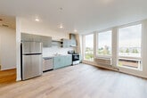 Located at 401 Union Ave SE in Olympia, WA, this thoughtfully designed 2-bedroom, 1-bathroom unit offers a clean, modern aesthetic throughout. Light wood-tone flooring runs continuously across the space, complementing the bright white walls and creating a cohesive, contemporary feel.

The open-plan kitchen and living area serves as the heart of the unit, featuring sage-toned flat-front cabinetry, stainless steel appliances including a refrigerator, dishwasher, and range with hood, plus generous counter space. Large floor-to-ceiling windows bathe the living area in natural light while framing elevated views of the surrounding Olympia cityscape.

Both bedrooms are well-proportioned and share the same warm flooring and large windows that invite natural light and outdoor views. The primary bedroom offers a comfortable footprint suitable for a full furniture arrangement.

A central hallway connects the living areas to the bedrooms and bathroom, with an impressive four closets distributed throughout the unit, providing exceptional storage. The bathroom includes a full bathtub and an in-unit washer is conveniently located nearby. Recessed lighting and Shaker-style interior doors with matte black hardware add refined finishing touches throughout.
