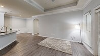 Located at 5375 Sugarloaf Pkwy in Lawrenceville, GA, this well-appointed 2-bedroom, 1-bathroom single-floor home offers a thoughtfully designed layout with quality finishes throughout. The open-concept living room immediately impresses with its tray ceiling, crown molding, elegant arched doorway, and a classic white-mantled fireplace — all complemented by durable wood-look flooring and a ceiling fan. The kitchen flows seamlessly from the living area and features rich cherry wood cabinetry, a green tile backsplash, stainless steel appliances including a refrigerator and microwave, and a granite-topped peninsula with an undermount sink — ideal for both cooking and casual dining. Both bedrooms are carpeted and offer ceiling fans, natural light from window views of lush greenery, and dedicated closet space. The full bathroom is finished with a granite-topped vanity, white cabinetry, brushed nickel hardware, and a large mirror with stylish overhead lighting, all set on wood-look flooring. A dedicated laundry room with full-size washer and dryer hookups adds everyday convenience. The home's neutral gray palette and consistent finishes create a cohesive, modern ambiance throughout.