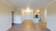 This single-floor residence offers a clean, modern aesthetic with consistent light-toned luxury vinyl plank flooring running throughout the entire space. The open-concept layout connects the living and dining areas seamlessly to the kitchen, creating a generous, airy feel ideal for everyday living and entertaining. A chandelier anchors the dining area, while the kitchen stands out with crisp white cabinetry, a light subway tile backsplash, stainless steel appliances including an electric range and over-the-range microwave, and a peninsula with a sink that doubles as a casual breakfast bar. Crown molding adds a refined detail to the main living spaces.

The living area features a ceiling fan with a light kit, direct outdoor access through a glass-paneled door, and a window that draws in natural light and greenery views. The bedrooms are well-proportioned, each equipped with ceiling fans and windows offering natural light and outdoor views. The primary bathroom provides a dual-sink vanity with white cabinetry and a large mirror, alongside a separate toilet and shower area. A secondary bathroom includes a single-sink vanity and a full shower-tub combination. Throughout, the neutral color palette and clean finishes create a bright, cohesive, and move-in-ready environment.