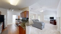 Located at 5200 Greystone Summit Dr in Columbus, Georgia, this well-appointed three-bedroom, two-bathroom home spans two floors and offers a thoughtfully designed layout suited for comfortable everyday living. The main living area features an open-concept arrangement connecting the kitchen, dining room, and living room. The kitchen is outfitted with rich cherry wood cabinetry, dark granite countertops with a tile backsplash, stainless steel appliances, and warm hardwood flooring. A peninsula with matching granite transitions seamlessly into the living space, which features plush carpet, a ceiling fan, vaulted tray ceilings with crown molding, and multiple windows and a glass door that invite abundant natural light and views of the outdoors. The generously sized primary bedroom offers dual windows, a ceiling fan, and soft carpet underfoot, while its en-suite bathroom includes a lengthy dual-sink vanity with granite countertops and white cabinetry. Four closets throughout the home provide ample storage, including walk-in closets with built-in wire shelving. A dedicated laundry room with hardwood flooring accommodates a full-size washer and dryer. The attached garage features an automatic opener and concrete flooring, completing this functional and inviting home.