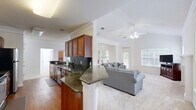 Located at 5200 Greystone Summit Dr in Columbus, Georgia, this well-appointed three-bedroom, two-bathroom home spans two floors and offers a thoughtfully designed layout suited for comfortable everyday living. The main living area features an open-concept arrangement connecting the kitchen, dining room, and living room. The kitchen is outfitted with rich cherry wood cabinetry, dark granite countertops with a tile backsplash, stainless steel appliances, and warm hardwood flooring. A peninsula with matching granite transitions seamlessly into the living space, which features plush carpet, a ceiling fan, vaulted tray ceilings with crown molding, and multiple windows and a glass door that invite abundant natural light and views of the outdoors. The generously sized primary bedroom offers dual windows, a ceiling fan, and soft carpet underfoot, while its en-suite bathroom includes a lengthy dual-sink vanity with granite countertops and white cabinetry. Four closets throughout the home provide ample storage, including walk-in closets with built-in wire shelving. A dedicated laundry room with hardwood flooring accommodates a full-size washer and dryer. The attached garage features an automatic opener and concrete flooring, completing this functional and inviting home.