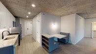 Located in Chicago's vibrant River North neighborhood, this single-floor unit at 675 N Wells Street showcases an industrial-modern aesthetic defined by its signature exposed concrete ceilings, which add raw architectural character throughout the space. Wide-plank hardwood-style flooring runs continuously, unifying the open layout and complementing the clean white walls.

The living area is a standout, featuring expansive floor-to-ceiling sliding glass doors that open to a private balcony with sweeping views of the Chicago skyline. The open layout also accommodates a built-in dining nook with a compact table and upholstered booth seating in a bold blue finish, paired with a shelving unit that provides functional storage without sacrificing style.

The kitchen is efficiently designed with white shaker-style cabinetry, quartz countertops, a herringbone tile backsplash, stainless steel appliances including a gas range and French door refrigerator, and gold-accented hardware that adds a refined touch.

The bathroom features white subway tile surrounding the tub and shower, matte black fixtures, a gray vanity with quartz countertop, and a backlit vanity mirror, creating a crisp, contemporary feel. Recessed lighting throughout ensures well-lit, functional spaces across the entire unit.