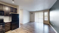 Located at 5151 S Rio Grande St in Littleton, Colorado, this one-bedroom, one-bathroom residence offers a well-organized single-level layout. The open-concept living and dining area is finished with durable hardwood-style flooring and neutral-toned walls, creating a bright and welcoming atmosphere. A sliding glass door with vertical blinds floods the living space with natural light while providing access to the outdoors.

The kitchen is a functional highlight, featuring rich dark espresso cabinetry that extends to the ceiling for ample storage, light countertops, a tile backsplash, and a full suite of black appliances including a range, microwave, dishwasher, and refrigerator. Track lighting overhead adds a modern touch.

The bedroom offers a comfortable retreat with plush carpeting, a ceiling fan, a large window with natural light, and a bold accent wall. A dedicated closet provides practical storage. The bathroom is finished with wood-look tile flooring, dark vanity cabinetry with a white countertop, and a full tub-shower combination with clean white tile surround. Throughout the residence, consistent finishes and a neutral color palette contribute to a cohesive and move-in-ready aesthetic.