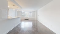 Located at 333 S Glebe Rd in Arlington, Virginia, this single-floor unit offers a well-organized, open layout designed for comfortable living. The living area is generously proportioned, featuring polished parquet flooring that extends throughout the main spaces, crisp white walls, and structural ceiling beams that add architectural character. A large window allows natural light to fill the room while providing views of the surrounding greenery, and a wall-mounted HVAC unit ensures year-round climate control.

The kitchen is a standout feature, thoughtfully designed with warm wood cabinetry, light quartz countertops, and a herringbone-patterned tile backsplash. Stainless steel appliances—including a gas range, over-the-range microwave, and refrigerator—are complemented by a skylight that brightens the space. A peninsula with open shelving connects the kitchen to the living area, creating a seamless flow ideal for both daily use and entertaining.

The bathroom is finished with floor-to-ceiling taupe subway tile surrounding a soaking tub, lending a clean, contemporary aesthetic. Throughout the unit, the neutral color palette and consistent design elements create a cohesive, modern ambiance.