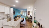 This single-story residence features an open-concept layout connecting the kitchen, dining, and living areas, creating a cohesive and functional flow. The kitchen is outfitted with white shaker-style cabinetry, granite countertops, a full suite of stainless steel appliances, a subway tile backsplash, and a peninsula that doubles as a dining surface. Wood-look flooring runs throughout the main living areas, adding warmth and continuity. The dining area accommodates a granite-topped table adjacent to the kitchen, while a utility cart provides additional storage nearby. The living room is defined by a bold teal accent wall, ceiling fan, recessed lighting, and French doors that invite natural light and offer outdoor access. The bedroom features plush carpeting, a ceiling fan, and a hallway leading to additional storage and the rest of the unit. The bathroom includes granite countertops, white cabinetry, wood-look flooring, and a full tub-shower combination with floor-length curtains. Throughout the space, neutral walls are complemented by thoughtful design details, resulting in a bright, cohesive interior.