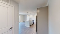 Located at 2274 5th Ave in Marion, Iowa, this thoughtfully designed two-bedroom, one-bathroom unit offers a clean, modern aesthetic throughout its single-floor layout. The open-concept kitchen flows seamlessly into the living area, anchored by a center island with granite-look countertops, pendant lighting, gray shaker-style cabinetry, and black appliances. Wood-style plank flooring extends throughout the main living areas, adding warmth and continuity to the space. The living room is bright and welcoming, highlighted by French doors that open to a private balcony with outdoor views, inviting natural light deep into the interior. Both bedrooms are carpeted for comfort, with the primary bedroom featuring a ceiling fan, a window with exterior views, and access to a generously sized walk-in closet fitted with wire shelving systems. A second walk-in closet provides additional storage. The bathroom is finished with tile flooring and includes a full tub-shower combination. The kitchen also offers a clear sightline down a hallway leading to the bedrooms, creating an efficient and connected floor plan. Neutral tones throughout the unit lend a clean, move-in-ready feel to this well-appointed Marion residence.