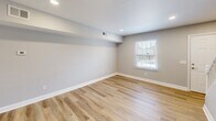 Located at 500 Savannah St in Greensboro, NC, this two-story, 2-bedroom, 2-bathroom home offers a well-organized layout spread across two floors. The main level features a bright living area with light hardwood-style flooring, recessed lighting, and neutral gray walls that create a clean, modern aesthetic. A sliding glass door fills the space with natural light and opens to a view of lush, wooded surroundings. The kitchen is well-appointed with white shaker-style cabinetry, light countertops, stainless steel appliances including a refrigerator, dishwasher, and range, and matching hardwood-style flooring that ties the main living areas together cohesively. Both bedrooms are finished with plush carpeting and large windows fitted with blinds that invite natural light while maintaining privacy. The primary bedroom stands out with dual louvered bi-fold closets, offering generous storage. The second bedroom also features ample closet space. The bathrooms include a full tub-and-shower combo with white tile surround and brushed nickel fixtures. A connecting hallway links the rooms efficiently across both levels, completing a practical and comfortable floor plan.