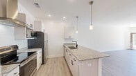 Located at 15000 Penmon Dr in Fuquay-Varina, NC, this thoughtfully designed single-story residence offers 1 bedroom and 2 bathrooms across a well-utilized floor plan. The open-concept kitchen and living area serves as the heart of the home, showcasing a galley-style kitchen with crisp white cabinetry, granite countertops, stainless steel appliances including a refrigerator, range, and built-in microwave, and a peninsula with an undermount sink and stylish pendant lighting overhead. Light wood-look flooring extends throughout the main living spaces, enhancing the bright, airy atmosphere. The living room receives natural light through a glass-panel entry door and is equipped with a ceiling fan. The bedroom features plush carpeting, natural light from dual windows, and its own ceiling fan, while offering direct access to a spacious walk-in closet with built-in shelving. Two full bathrooms serve the unit, one featuring a tub-shower combination with light wood-look flooring. Clean white walls, recessed lighting, and modern black hardware fixtures tie the space together with a cohesive, contemporary aesthetic throughout.