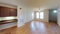 This single-story residence offers a well-organized layout with a clean, functional design throughout. The living area is an open, airy space finished with warm wood-look laminate flooring that extends underfoot, complemented by a ceiling fan overhead and natural light streaming in through dual windows near the entry door, creating a bright and welcoming atmosphere. A pass-through counter connects the living space to the kitchen, adding a sense of openness between the two areas.

The galley-style kitchen is efficiently designed, featuring medium-toned wood cabinetry lining both walls, dark laminate countertops, and a stainless steel sink. White appliances, including a coil-burner range, built-in microwave, refrigerator, and dishwasher, are all included. Light wood-look flooring continues through this space, and overhead lighting ensures the kitchen remains well-lit throughout the day.

The bedrooms are finished with plush neutral carpeting and ceiling fans, offering a comfortable and quiet retreat. Each room provides adequate wall space and natural light. The bathroom features a full tub-shower combination with white tile surround, wood-look flooring, a dark-countered vanity, and clean, neutral walls that contribute to a simple, functional finish throughout the home.
