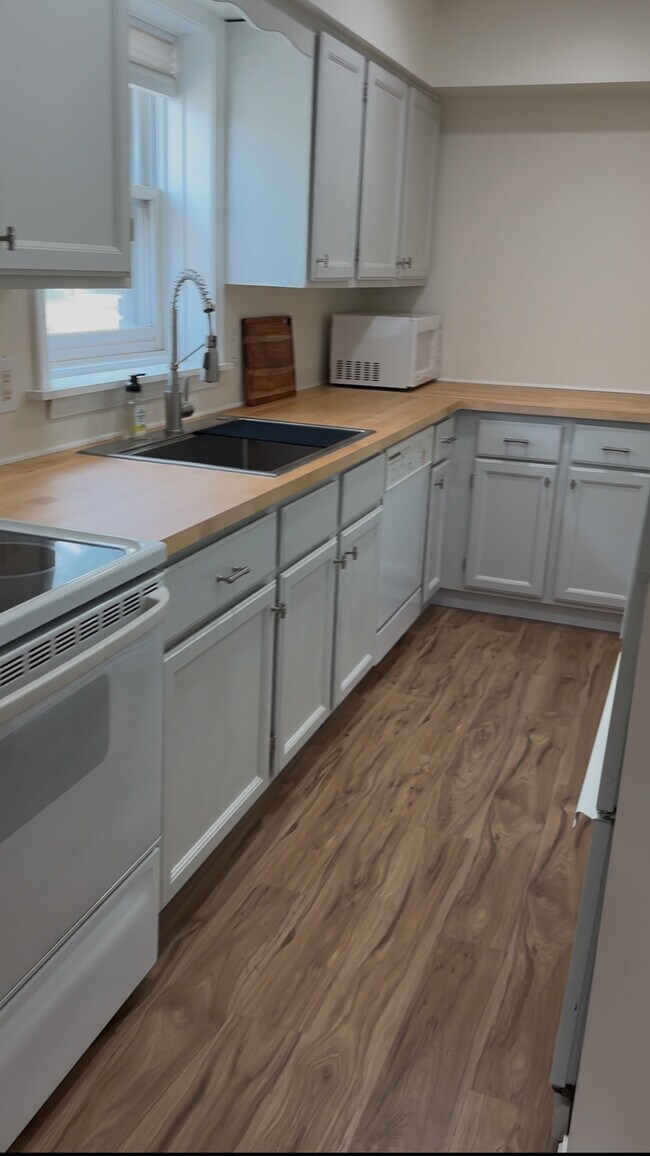 Cocina lineal luminosa con encimeras de madera, grifo moderno, electrodomésticos completos y luz natural. - 328 N Allen St