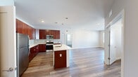 Located at 1008 Matthew Rd in Morganville, NJ, this single-floor home offers four bedrooms and two bathrooms across a thoughtfully designed layout. The open-concept kitchen and living area serves as the heart of the home, featuring rich mahogany-toned cabinetry, stainless steel appliances, a tile mosaic backsplash, and a central island with a white quartz countertop and undermount sink, illuminated by stylish pendant lighting. Wood-look flooring flows seamlessly throughout the main living areas, lending warmth and continuity. The spacious living room is bathed in natural light from large windows and offers direct access to an exterior door. The generously sized primary bedroom includes a walk-in closet with wire shelving and an en-suite bathroom appointed with a glass-enclosed shower, floor-to-ceiling tile surround, granite countertops, and hardwood-style flooring. The second bathroom features a soaking tub with a tiled surround and a granite vanity. The additional bedrooms are carpeted and filled with natural light from bright windows with blinds. A dedicated closet provides supplemental storage, and hallways connect the layout efficiently. The home presents a clean, modern aesthetic with neutral tones throughout.