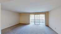 This two-bedroom, two-bathroom residence in Grand Blanc, Michigan offers a well-organized single-floor layout with a thoughtful mix of living spaces. The entrance welcomes you into a home that flows naturally between functional areas.

The living room is generously sized, featuring wall-to-wall carpet and a large sliding glass door framed by vertical blinds that floods the space with natural light and provides direct access to a private balcony. Adjacent to the living room, the dining area is distinguished by an elegant brass chandelier and chair-rail molding detail along the walls, adding a classic touch.

The kitchen is equipped with light oak cabinetry, granite-toned laminate countertops, and black appliances including a refrigerator, electric range, and dishwasher. Light tile flooring and a double-basin sink complete the functional cooking space.

Both bedrooms are carpeted and well-proportioned, with the primary bedroom offering a notably spacious footprint. Windows with vertical blinds provide natural light to the sleeping areas. The unit includes six closets total, ensuring ample storage throughout.

The two bathrooms each feature a tub-shower combination. A utility room and hallway round out the layout, making this a complete and practical residence in a convenient Michigan location.