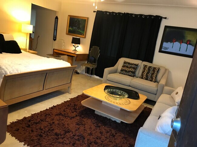 Studio with 2 couches, coffee table, queen bed, table with four chairs. - 345 9th Ave NE