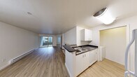 Located at 600 7th Ave in the heart of Seattle, this one-bedroom, two-bathroom residence offers a practical and well-appointed single-floor layout. The open-concept kitchen and living area forms the core of the unit, where light wood-style flooring runs throughout. The kitchen features white cabinetry, dark countertops, a stainless steel sink, and a dishwasher, arranged along a peninsula that separates it from the living space. The living room is highlighted by a fireplace with a classic surround and a sliding glass door that opens onto a private balcony, bringing in natural light. Baseboard heating is present throughout the unit. The bedroom is carpeted and includes a ceiling fan, a window with blinds that allows natural light, and a closet with mirrored sliding doors. An adjacent vanity area with a sink and mirror connects conveniently to the bathroom, which includes a full soaking tub with a shower. A dedicated in-unit laundry room provides side-by-side washer and dryer hookups with additional shelving. Clean white walls and a neutral palette lend a bright, move-in-ready feel throughout this efficiently designed Seattle residence.