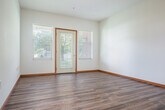 Located at 201 S Madison St in Waunakee, WI, this single-floor, 2-bedroom, 2-bathroom residence offers a practical and comfortable layout. The open-concept living, dining, and kitchen area forms the heart of the home, with durable hardwood-style flooring running throughout the main living spaces. A ceiling fan adds both function and comfort to the living area. The kitchen is well-equipped with warm oak cabinetry offering ample storage, white appliances including a refrigerator, range, microwave, and dishwasher, and a peninsula counter that provides additional workspace and casual seating. A private entry door in the living area is flanked by windows, flooding the space with natural light and offering pleasant views of the surrounding greenery. The two bedrooms feature neutral carpet, crisp white walls, and windows overlooking the landscaped exterior. Both rooms include closet space for storage. Warm wood-toned door and window trim is consistent throughout, tying the interior together with a cohesive, classic aesthetic. Two full bathrooms serve the unit. The property sits on a well-maintained lot with mature trees, providing a serene residential setting in the heart of Waunakee.