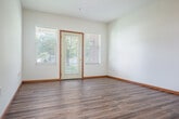 Located at 201 S Madison St in Waunakee, WI, this single-floor, 2-bedroom, 2-bathroom residence offers a practical and comfortable layout. The open-concept living, dining, and kitchen area forms the heart of the home, with durable hardwood-style flooring running throughout the main living spaces. A ceiling fan adds both function and comfort to the living area. The kitchen is well-equipped with warm oak cabinetry offering ample storage, white appliances including a refrigerator, range, microwave, and dishwasher, and a peninsula counter that provides additional workspace and casual seating. A private entry door in the living area is flanked by windows, flooding the space with natural light and offering pleasant views of the surrounding greenery. The two bedrooms feature neutral carpet, crisp white walls, and windows overlooking the landscaped exterior. Both rooms include closet space for storage. Warm wood-toned door and window trim is consistent throughout, tying the interior together with a cohesive, classic aesthetic. Two full bathrooms serve the unit. The property sits on a well-maintained lot with mature trees, providing a serene residential setting in the heart of Waunakee.