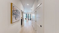 Located in Canton, GA, this thoughtfully designed single-floor unit offers a compact yet functional layout that maximizes every square foot. The open-concept kitchen and living area serves as the heart of the space, where the kitchen impresses with crisp white cabinetry accented by gold hardware, a textured tile backsplash, stainless steel appliances, light wood-style flooring, and a central island with seating for two — illuminated by stylish pendant lighting. The adjacent living area features notably tall ceilings with a recessed nook housing a ceiling fan, adding architectural character and a sense of vertical openness. Natural light filters in through large windows dressed with patterned curtains, creating a warm and inviting atmosphere. The bathroom is outfitted with a full soaking tub and shower combination, framed by elegant patterned curtains and a glass corner shelf, delivering a clean, spa-like feel. The walk-in closet provides practical storage with multi-tiered white wire shelving systems and soft carpet underfoot. Together, these spaces combine modern finishes with efficient design to create a comfortable, move-in-ready living environment.