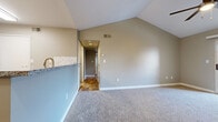 This single-floor residence showcases a thoughtful layout with a variety of updated finishes throughout. The spacious living area is highlighted by dramatic vaulted ceilings, a ceiling fan, and a corner fireplace with a clean white mantel. Sliding glass doors open to a private balcony, allowing natural light to fill the room, which is finished with plush wall-to-wall carpeting in a neutral tone.

The kitchen is well-appointed with white cabinetry, granite-look countertops, a classic white subway tile backsplash, and stainless steel appliances including a range, microwave, and refrigerator. Light wood-look plank flooring runs throughout the kitchen and connects to the adjacent dining or entry areas.

The bedrooms feature soft carpeting, ample natural light, and sliding-door closets with built-in hanging rods for convenient storage. Neutral gray walls throughout the residence create a cohesive and modern aesthetic.

Two bathrooms serve the home: one featuring a soaking tub with tiled surround, and a second with a walk-in shower and granite-topped vanity. Both bathrooms include wood-look flooring for a clean, contemporary finish. The overall design combines functional layout with modern updates, offering a comfortable and move-in-ready living environment.