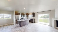 Located at 601 County U in Wrightstown, Wisconsin, this well-appointed single-floor home offers a thoughtfully designed layout across two bedrooms, three bathrooms, and two closets. The open-concept kitchen and living area serves as the heart of the home, featuring soaring vaulted ceilings that enhance the sense of space and airiness. The kitchen is outfitted with dark espresso cabinetry, granite countertops, stainless steel appliances, and a central island with additional seating — all set atop light-toned hardwood-style flooring that flows seamlessly throughout. Large sliding glass doors and multiple windows flood the space with abundant natural light and provide open views of the surrounding green landscape. The living room is anchored by a modern corner fireplace and includes a wall-mounted split unit, adding both comfort and style. The spacious primary bedroom features vaulted ceilings and a ceiling fan, while the secondary bedroom offers a bright window and baseboard heating. The bathrooms are finished with matching granite vanities and dark cabinetry, maintaining a consistent, modern aesthetic. Two dedicated closets provide practical storage solutions, completing this clean, contemporary home.