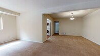 Located at 736 Camberwell Circle in Towson, Maryland, this single-floor residence offers a thoughtfully arranged layout with generous living spaces throughout. The interior is finished with warm neutral-toned walls and plush wall-to-wall carpeting across the main living and sleeping areas, creating a cohesive and comfortable atmosphere.

The expansive main living area is bright and open, featuring a large picture window that frames views of the surrounding greenery and allows abundant natural light to fill the room. A pendant light fixture accents a secondary living or dining area, adding a polished touch to the open-plan design. The layout flows naturally, with a foyer entry visible from the main living space.

The kitchen is well-appointed with rich warm-toned wood cabinetry, white countertops, and hardwood flooring. It includes a full suite of white appliances — refrigerator, range with over-the-range microwave, and dishwasher — along with a window above the sink providing additional natural light.

A dedicated laundry area features a stacked washer and dryer unit conveniently located within the residence, adding a practical in-home amenity. The bedroom is spacious and carpeted, offering a walk-in closet and an additional closet, providing ample storage. One room also features a distinctive skylight detail in the ceiling, lending architectural interest and brightness to the space.
