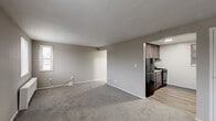 Located at 1553 Parkline Dr in Pittsburgh, PA, this one-bedroom, one-bathroom unit offers a practical and efficiently designed single-floor layout. The space is organized around a central hallway that connects all rooms, providing a logical and easy-to-navigate flow throughout.

The generously sized bedroom features soft wall-to-wall carpeting in a neutral gray tone, warm taupe-painted walls, and two windows that allow natural light to fill the room. A radiator unit beneath the windows provides reliable heating. The bedroom also benefits from direct access to a dedicated closet for ample storage.

The living area continues the carpeted flooring and neutral color palette, offering an open and versatile space that transitions seamlessly into the kitchen. The kitchen is compact yet well-appointed, featuring dark gray shaker-style cabinetry, granite-style countertops, a stainless steel sink, a black gas range, and a full-size black refrigerator. Wood-look vinyl flooring grounds the kitchen with a clean, modern feel.

The bathroom is finished with wood-look vinyl flooring, white tile surround walls, a full tub-shower combination with chrome fixtures, a toilet, and a pedestal sink, keeping the space bright and functional.

Overall, this unit presents a clean, neutral aesthetic with updated finishes throughout, making it a practical and comfortable Pittsburgh residence.