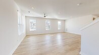 This two-story home on Pisano Street in Mount Juliet, Tennessee, presents a clean, modern aesthetic defined by a neutral color palette, light hardwood-style flooring, and an abundance of natural light. The main level opens into a welcoming entryway with light wood flooring that flows seamlessly into the living areas. The spacious living room is lined with multiple windows fitted with white blinds, allowing ample daylight to fill the room, and is finished with recessed lighting and a ceiling fan overhead.

The kitchen is a standout feature, showcasing white shaker-style cabinetry, quartz countertops, a central island, stainless steel appliances including a refrigerator and dishwasher, a farmhouse-style sink, and pendant lighting. A dedicated laundry room with wire shelving and hardwood-style flooring adds everyday convenience.

Upstairs, the bedrooms are carpeted in a warm neutral tone and feature windows with exterior views. The primary suite includes a walk-in closet with wire shelving and an en-suite bathroom equipped with a double-sink vanity featuring quartz countertops, white cabinetry, a glass-enclosed walk-in shower, and tile flooring. The home's bright, move-in-ready condition and thoughtful layout make it an inviting residence.
