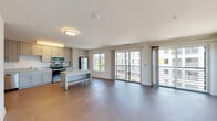 This well-appointed single-floor residence offers a thoughtfully designed open-concept layout that seamlessly connects the kitchen and living areas. The kitchen is equipped with stainless steel appliances, including a refrigerator, range, and over-the-range microwave, complemented by warm-toned shaker-style cabinetry, granite countertops, and a mobile island with a butcher block top for additional workspace. Durable wood-look flooring runs throughout the main living areas, lending a clean and contemporary aesthetic.

The expansive living area is bathed in natural light, courtesy of multiple large sliding glass doors that open to a private balcony, offering views of the surrounding community. The open floor plan provides generous room to arrange living and dining spaces to suit various needs.

The bedroom features plush carpeting, a large closet, and a secondary door providing added privacy and flexibility. The full bathroom is finished with classic white subway tile surrounding the soaking tub and shower combination, accented by a decorative stone border tile and wood-look tile flooring, creating a clean and timeless design. A vanity with ample counter space completes the bathroom. The overall ambiance of the space is bright, modern, and move-in ready.