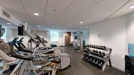 Located at 331 Justison Street in Wilmington, Delaware, this fitness center offers a thoughtfully designed exercise space that accommodates a wide variety of workout routines. The room features a clean, modern aesthetic with white walls, a drop-tile ceiling with recessed lighting, and durable rubber flooring throughout — all contributing to a functional and professional gym environment.

The cardio section is well-appointed with multiple treadmills and elliptical machines, including Precor and Life Fitness models, each equipped with individual display screens for an engaging workout experience. A large wall-mounted mirror expands the visual depth of the space and enhances the sense of openness. The strength training area includes a multi-station cable machine, a rack of free weights ranging in various sizes, medicine balls, stability balls, and exercise mats, providing ample options for resistance and functional training.

Natural light filters in through a window on one wall, complementing the overhead recessed lighting to keep the space bright and inviting. A water cooler station ensures hydration is always within reach. The layout is efficiently organized to allow users to move freely between equipment, making the most of the available floor space. Overall, this fitness center delivers a comprehensive and well-maintained facility for residents or guests seeking a convenient place to exercise.