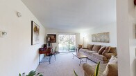 This well-organized single-floor residence offers two bedrooms and one bathroom within a efficiently utilized floor plan. The living room serves as the central gathering space, featuring neutral-toned carpet, white walls, and a standout sliding glass door that fills the room with natural light and provides direct access to an outdoor patio area with garden views. The open sightlines and bright atmosphere make the living area feel welcoming and spacious.

Adjacent to the living room, the combined kitchen and dining area transitions to hardwood-style flooring. The kitchen is equipped with white cabinetry, light granite-style countertops, a dishwasher, and standard appliances, offering a clean and functional workspace. The dining area accommodates a round wooden table beneath a ceiling fan with light fixture, creating a casual and comfortable setting for meals.

Both bedrooms are carpeted and feature vertical-blind windows that offer views of surrounding greenery, allowing natural light while maintaining privacy. The primary bedroom provides a comfortable retreat with adequate space for standard furnishings. The single bathroom includes a white vanity, tiled flooring, and a shower-tub combination. A dedicated closet completes the layout, adding practical storage to the unit.