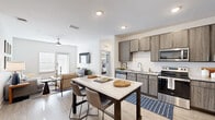 Located at 1050 Old Gilliard Rd in Ridgeville, SC, this single-story 2-bedroom, 2-bathroom home offers a thoughtfully designed open-concept layout with modern finishes and a cohesive, contemporary aesthetic throughout.

The kitchen is a standout feature, equipped with stainless steel appliances — including a refrigerator, range, and built-in microwave — complemented by wood-toned cabinetry, light granite-style countertops, a tile backsplash, and a center island with bar seating. It flows seamlessly into the living room, which features wood-look flooring, a ceiling fan, and access to an exterior door, creating a bright and connected living space.

The primary bedroom is a comfortable retreat with a ceiling fan, natural light from well-placed windows, and a spacious walk-in closet with wire shelving. The en-suite primary bathroom features a double-sink vanity with granite countertops, a soaking tub, and wood-look tile flooring. The second bedroom is equally well-lit and includes its own ceiling fan and closet access. The second bathroom mirrors the home's consistent finishes with a granite-topped vanity and wood-look flooring. A dedicated utility room rounds out the functional layout of this well-designed home.