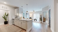 Located at 250 Victor Ave in Greer, SC, this thoughtfully designed 2-bedroom, 2-bathroom residence offers a comfortable and modern living experience on a single floor. The open-concept kitchen and living room serve as the heart of the home, featuring a granite-topped island with bar seating, crisp white cabinetry with subway tile backsplash, stainless steel appliances, and stylish pendant lighting. Light wood-style flooring flows seamlessly throughout the main living areas, enhancing the bright, airy atmosphere. The living room is anchored by a ceiling fan and floor-to-ceiling sliding glass doors dressed with vertical blinds, allowing generous natural light and outdoor views. Both bedrooms are carpeted and well-lit, with large windows featuring plantation shutters and ceiling fans. The primary bedroom offers a comfortable, retreat-like feel with ample space. Each bathroom is clean and modern, with one featuring a spacious glass-enclosed walk-in shower. A dedicated laundry area houses a stacked washer and dryer unit for added convenience. Dark-paneled interior doors throughout the residence provide a striking contrast to the light, neutral color palette, lending a contemporary and cohesive design sensibility to the entire space.