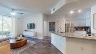 Located in Miramar, Florida, this well-appointed single-floor residence offers a thoughtfully designed open-concept layout that seamlessly connects the living, dining, and kitchen areas. Rich wood-style flooring flows throughout the main living spaces, complemented by crisp white walls and abundant natural light streaming through large windows and sliding glass doors.

The kitchen serves as a central hub, showcasing granite countertops, a spacious peninsula with an undermount sink, stainless steel appliances including a refrigerator, microwave, and range, white cabinetry, and a teal subway tile backsplash. Track lighting overhead adds both function and style. Adjacent to the kitchen, the dining area features a cozy nook with teal accent walls, floating shelves, and a large mirror that enhances the sense of depth.

The living room is bright and inviting, with a sliding glass door opening to an outdoor view and a stylish pendant light as a focal point. The primary bedroom offers a serene retreat with a ceiling fan, large windows with sheer curtains, and dark accent walls for contrast. A second bedroom includes a walk-in closet for ample storage. The bathroom is finished with granite vanity counters, white cabinetry, and tile flooring. A dedicated in-unit laundry area with full-size washer and dryer adds everyday convenience.
