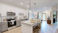 Located in Jacksonville, FL, this single-story 2-bedroom, 2-bathroom home offers a thoughtfully designed open-concept layout that maximizes both functionality and style. The heart of the home is a modern kitchen that flows seamlessly into the dining and living areas. It features crisp white upper cabinetry, sage-toned lower cabinets, a classic subway tile backsplash, stainless steel appliances, and a generous granite-topped island with bar seating illuminated by pendant lighting — ideal for casual dining and entertaining. Light wood-tone flooring runs throughout the main living areas, enhancing the bright, airy atmosphere. The living room is bathed in natural light through large windows and a glass door, creating an inviting, open feel. The spacious primary bedroom offers a comfortable retreat with a walk-in closet outfitted with wire shelving systems and dedicated storage. The primary bathroom features a granite-topped vanity with white cabinetry, a framed mirror, and a tub-shower combination with white tile surround. The second bedroom is equally well-lit, with a window and neutral finishes. A dedicated laundry area and two closets add practical convenience throughout. Recessed lighting and ceiling fans complete the home's clean, contemporary aesthetic.