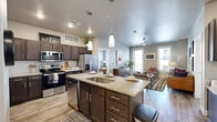Located at 8225 Dorado Dr in Odessa, TX, this well-appointed 2-bedroom, 2-bathroom residence offers a thoughtfully designed single-level layout. The open-concept kitchen and living area serves as the heart of the home, featuring wood-look plank flooring, dark espresso cabinetry, granite countertops, stainless steel appliances, and a central island with bar seating illuminated by pendant lighting. The living room is bright and welcoming, with large windows that invite natural light, a ceiling fan, and direct access to a private outdoor area. The primary bedroom is generously sized, showcasing plush carpet, multiple windows with exterior views, and a ceiling fan. Its en-suite bathroom features a granite-topped vanity with dark cabinetry, wood-look flooring, and a glass-enclosed shower. The second bedroom is equally comfortable, with large windows and soft carpet flooring. A second full bathroom mirrors the refined finishes found throughout, with a granite vanity and tasteful tile work. Neutral gray tones on the walls complement the warm wood and granite elements, creating a cohesive and modern aesthetic. A dedicated closet adds practical storage, rounding out this efficiently designed and visually polished residence.