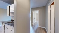 This 1-bedroom, 1-bathroom unit in Surrey, BC offers a practical and comfortable layout across a single floor. Light-toned hardwood flooring runs throughout the space, complementing the neutral, warm-beige walls and crisp white trim that create a clean, cohesive aesthetic.

The living room is generously proportioned and serves as the heart of the unit. Large sliding glass doors flood the space with natural light and open onto a private balcony overlooking mature trees, providing a pleasant outdoor connection. A baseboard heating system ensures year-round comfort, and a textured ceiling adds subtle character to the room.

The kitchen is positioned adjacent to the living area and features white cabinetry with tile backsplash detailing, providing efficient storage and workspace. A hallway connects the main living areas to the private quarters, maintaining a clear separation between living and sleeping spaces.

The bedroom is a well-sized private retreat, benefiting from a large window that frames views of the surrounding greenery and allows ample natural light. A mirrored sliding-door closet provides practical built-in storage with shelving and hanging space, while a baseboard heater ensures comfort throughout the seasons.

Overall, the unit offers a bright, neutral palette and functional design well-suited for comfortable everyday living in Surrey, BC.