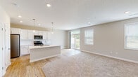 This two-story home in Lake Elmo, Minnesota offers a thoughtfully designed layout spread across two well-appointed floors. The main level centers around an open-concept living and kitchen area, where light hardwood flooring flows seamlessly from the kitchen into the living space, which transitions to plush carpeting. The kitchen is outfitted with crisp white shaker-style cabinetry, light quartz countertops, a large island with an undermount sink, pendant lighting, and a full suite of stainless steel appliances including a gas range, microwave, and refrigerator. Sliding glass doors and a window in the living area invite natural light and provide outdoor views. A staircase with wood treads connects the two floors. The upper level features carpeted bedrooms, including a spacious walk-in closet with wire shelving. Two full bathrooms are finished with white cabinetry, quartz countertops, and tile flooring — one with a walk-in glass-enclosed shower and the other with a shower-tub combination. A dedicated laundry room houses a full-size washer and dryer. Additional highlights include recessed lighting throughout, a generously sized lower-level bonus room with hardwood and carpet flooring, and ample storage throughout the home.