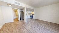 This single-floor, 1-bedroom, 1-bathroom unit offers a practical and thoughtfully designed layout with consistent light wood-style flooring running throughout every room. The open-concept living and kitchen area forms the heart of the unit, with the living space featuring painted brick accent walls and a sliding glass door that invites natural light and provides exterior access. The kitchen is efficiently appointed with white shaker-style cabinetry, granite-look countertops, a stainless steel refrigerator, and a stainless steel gas range with an overhead ventilation hood — offering a clean, modern aesthetic. A dedicated hallway connects the main living area to the private quarters, leading to a closet and the full bathroom, which features marble-style tiled walls surrounding a soaking tub. The bedroom is a well-sized private retreat, highlighted by painted brick walls, a window with vertical blinds that allow for natural light, and a ceiling vent for climate control. The unit's consistent neutral color palette of whites and light grays, combined with the wood-style flooring, creates a bright and cohesive atmosphere throughout the space.