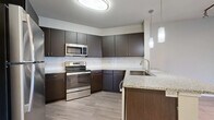 This thoughtfully designed one-bedroom, one-bathroom residence in Addison, Texas offers a functional and modern living experience across a single floor. The open-concept layout seamlessly connects the living area to the kitchen, creating an airy and cohesive space ideal for everyday living and entertaining.

The kitchen is a standout feature, boasting rich dark espresso cabinetry, granite countertops, a classic white subway tile backsplash, and stainless steel appliances including a range, microwave, and refrigerator. A peninsula with a built-in sink and pendant lighting above adds both style and practicality.

The living area features light wood-style flooring, track lighting, and neutral tones that carry throughout the space. A ceiling fan adds comfort, and French doors with sidelight panels invite natural light while providing access to the outdoors.

The bedroom is a comfortable retreat, featuring the same warm flooring and a dedicated walk-in closet equipped with multi-tiered shelving and hanging rods for ample storage. The bathroom offers a full soaking tub with a tiled surround, wood-style flooring, and clean white fixtures. A hallway connects all areas efficiently, completing this well-organized and move-in-ready home.