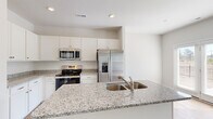 Located in Northwest, NC, this two-story home offers three bedrooms, three bathrooms, and a thoughtfully distributed layout across two generously sized floors. The main level provides an open and airy living area with light hardwood-style flooring that flows throughout, complemented by large windows that invite abundant natural light. The kitchen is a standout feature, showcasing granite countertops with a double-basin sink, white shaker cabinetry, and a full suite of stainless steel appliances including a range, microwave, and French door refrigerator. Upstairs, the spacious primary bedroom includes a ceiling fan, natural light from a dedicated window, and access to a well-appointed en-suite bathroom featuring a dual-sink vanity with white cabinetry, a glass-enclosed shower, and wood-look flooring. Each bedroom is generously sized, fitted with ceiling fans, and supported by walk-in closets with built-in wire shelving systems. A dedicated laundry room with a full-size washer and dryer adds everyday convenience. The upper hallway features an open landing with clean railings. The attached garage offers a spacious concrete-floored area with an automatic opener. Throughout, the home maintains a clean, modern aesthetic with neutral tones and consistent finishes.