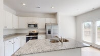 Located in Northwest, NC, this two-story home offers three bedrooms, three bathrooms, and a thoughtfully distributed layout across two generously sized floors. The main level provides an open and airy living area with light hardwood-style flooring that flows throughout, complemented by large windows that invite abundant natural light. The kitchen is a standout feature, showcasing granite countertops with a double-basin sink, white shaker cabinetry, and a full suite of stainless steel appliances including a range, microwave, and French door refrigerator. Upstairs, the spacious primary bedroom includes a ceiling fan, natural light from a dedicated window, and access to a well-appointed en-suite bathroom featuring a dual-sink vanity with white cabinetry, a glass-enclosed shower, and wood-look flooring. Each bedroom is generously sized, fitted with ceiling fans, and supported by walk-in closets with built-in wire shelving systems. A dedicated laundry room with a full-size washer and dryer adds everyday convenience. The upper hallway features an open landing with clean railings. The attached garage offers a spacious concrete-floored area with an automatic opener. Throughout, the home maintains a clean, modern aesthetic with neutral tones and consistent finishes.