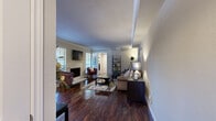 This thoughtfully designed single-floor residence offers a seamless blend of comfort and modern finishes across its efficiently organized layout. The open-concept living, dining, and kitchen area forms the heart of the home, anchored by rich dark hardwood flooring that extends throughout the main living spaces. The living room features crown molding, a tray ceiling detail, and a wood-burning fireplace framed by a classic tile surround, creating a warm and inviting atmosphere. Natural light filters in through plantation-shuttered windows, enhancing the neutral color palette throughout.

The kitchen is equipped with stainless steel appliances, white cabinetry with a mosaic tile backsplash, and a granite-topped breakfast bar that doubles as a casual dining space. A dedicated dining area sits adjacent, offering an intimate setting for meals.

The bedroom is carpeted for comfort and includes a ceiling fan, generous natural light from a large window with blinds, and direct access to a spacious walk-in closet outfitted with dual hanging rods and shelving. The bathroom features granite countertops, white cabinetry, and a fully tiled soaking tub and shower combination with a decorative mosaic border accent. Dark hardwood flooring continues into the bathroom, maintaining a cohesive design aesthetic throughout the unit.