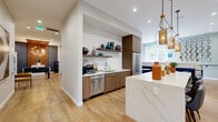 Located at 1324 Mill Creek Blvd in Mill Creek, WA, this thoughtfully designed single-floor space offers a generous and versatile layout across its entirety. The interior showcases a cohesive modern aesthetic, combining light hardwood flooring, recessed lighting, and a neutral color palette accented with bold design details throughout.

The expansive living area serves as the heart of the space, featuring a tile-surround fireplace, a wall-mounted TV, and large windows that invite abundant natural light and views of the surrounding greenery. Soft sage green walls, layered area rugs, and carefully curated décor create a warm yet sophisticated atmosphere. French doors provide a seamless connection to the outdoors.

An adjacent games and entertainment zone offers a foosball table, lounge seating, and a mounted TV set against a striking geometric navy accent wall, making it ideal for social gatherings.

The kitchenette is both functional and refined, boasting walnut cabinetry, a quartz waterfall island, stainless steel appliances, a textured white tile backsplash, floating shelves, and pendant lighting — all set against a backdrop of light hardwood floors.

The private office area features a dedicated workstation, patterned carpet flooring, and glass-walled meeting nooks that promote focus while maintaining visual openness. A connecting hallway ties all areas together with purposeful flow and clean architectural lines.