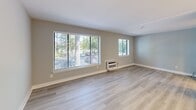 Located at 2809 West Glen Drive, Unit 21 in Falls Church, Virginia, this efficiently designed single-floor unit offers a well-planned open-concept layout combining a fully equipped kitchen and a bright living area. The space is finished with light wood-tone luxury vinyl plank flooring throughout, lending a clean, contemporary aesthetic that visually expands the interior.

The kitchen is a standout feature, designed as a galley-style space with crisp white shaker cabinetry, white quartz countertops, and a full suite of stainless steel appliances including a refrigerator, electric range, built-in microwave, and dishwasher. Pendant lighting above the kitchen counter adds a modern touch, while a pass-through peninsula connects the kitchen seamlessly to the living area.

The living room is open and airy, benefiting from multiple windows dressed with horizontal blinds that invite generous natural light and offer views of surrounding greenery. Soft gray-toned walls complement the neutral flooring, creating a calm and versatile canvas. A wall-unit HVAC system provides climate control directly within the living space. A mirrored closet is visible adjacent to the living area, adding both storage and the illusion of additional depth. The bathroom, visible from the layout overview, includes standard fixtures in a clean, updated finish consistent with the rest of the unit's modern renovations.