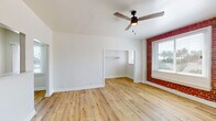 Located at 516 N Alvarado Blvd in Los Angeles, this single-story unit blends classic character with modern updates throughout its well-designed layout. Light-toned hardwood-style flooring runs continuously across the living areas, complementing crisp white walls and lending a clean, cohesive feel to the space.

The living room is a standout area, featuring vaulted ceilings, a ceiling fan with integrated lighting, and a striking exposed red brick accent wall that frames a large window. Natural light filters in generously, enhancing the open and airy atmosphere. A wall-mounted heater is integrated into the brick wall, adding a functional yet characterful detail.

An adjacent room—ideal as a bedroom—mirrors the living area's aesthetic with matching flooring, vaulted ceilings, another ceiling fan, and an open closet nook. A brick-framed window continues the architectural theme throughout.

The kitchen is efficiently arranged in a galley configuration, featuring gray shaker-style cabinetry, light countertops, a gas range, stainless steel refrigerator, and a pass-through window that connects visually to the living area. The flooring carries through seamlessly.

The bathroom is finished with floor-to-ceiling white subway tile surrounding the tub-shower combination, chrome fixtures, a single vanity with an integrated sink, and a frosted window providing privacy with natural light.