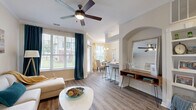 This thoughtfully designed single-floor residence offers a cohesive and comfortable living experience across a well-utilized floor plan. The open-concept living and dining area serves as the heart of the home, featuring warm wood-style flooring, crown molding, and ceiling fans throughout. Large windows flood the space with abundant natural light, while elegant teal drapes add a pop of color. An arched architectural accent wall adds character to the living area, which flows seamlessly into the dining space, illuminated by a stylish chandelier and framed by views of the outdoors.

The galley-style kitchen is efficiently designed with white cabinetry, stone-look countertops, stainless steel appliances, and a dual-basin sink — offering both functionality and a clean aesthetic. A breakfast bar connects the kitchen to the main living area.

The bedroom is a serene retreat with plush carpet flooring, two windows offering outdoor views, and a ceiling fan. It connects directly to the full bathroom, which features a double-sink vanity with stone countertops, wood-style flooring, and direct access to a dedicated walk-in closet.

Additional highlights include a private in-unit laundry room with a full-size washer and dryer, a dedicated hallway, and an entrance area — providing practical convenience throughout.